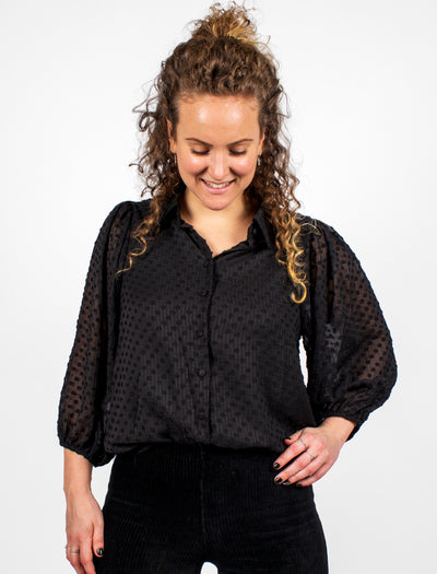 Zwarte blouse met transparante mouwen. De blouse heeft kleine pofdetails op de schouders en een driekwart mouw. De voorzijde van de blouse is gevoerd en de achterzijde is transparant. Deze blouse is ook beschikbaar in het off-white. 